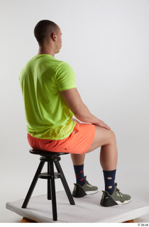 Joel  1 dressed green sneakers orange shorts sitting sports…